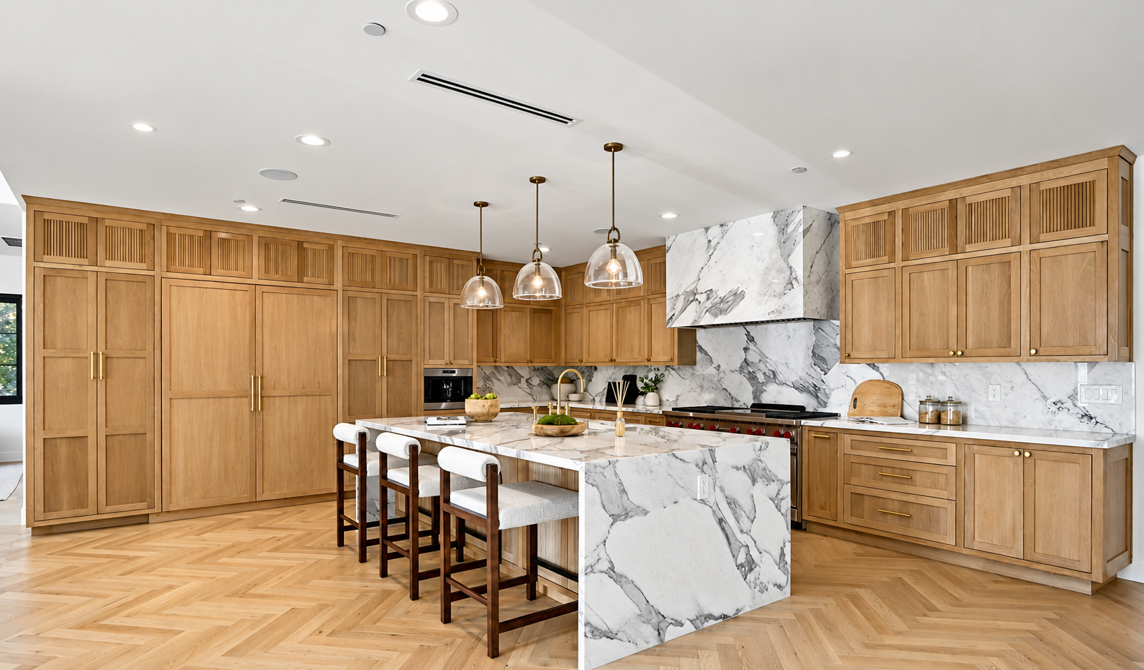 Luxury kitchen with a marble island, warm wood cabinetry, and pendant lighting